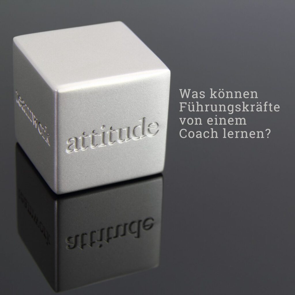 Würfel mit den Worten „attitude“ und „teamwork“ auf schwarzem Hintergrund, Symbol für Coaching-Haltung