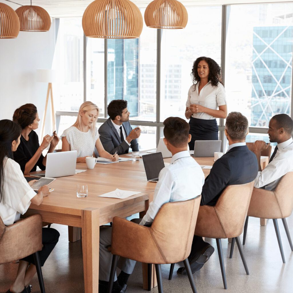 Führungskraft spricht mit ihrem Team in einem Meetingraum über Zusammenarbeit und Fragetechnik.