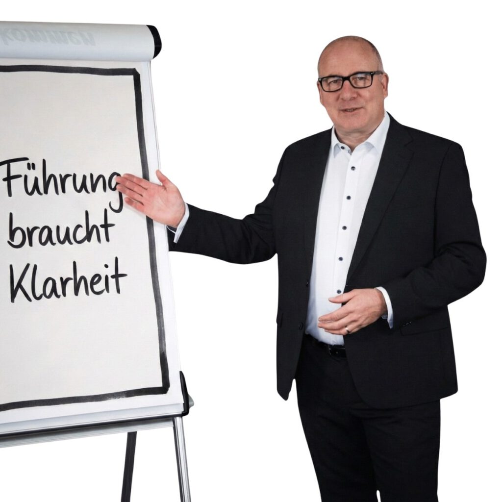 Porträt von Harald Braun, Business Coach für Führungskräfte. Er trägt einen dunklen Anzug und Brille, steht selbstbewusst vor einer Fensterfront mit Stadt-Silhouette.