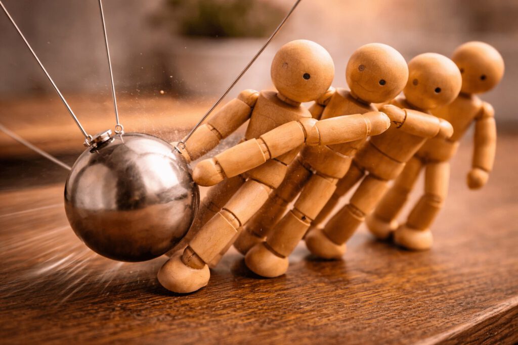 Ein Pendel stößt eine Gruppe von Figuren an und bringt Bewegung hinein.