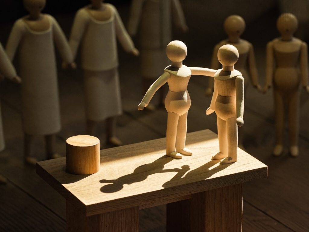 Symbolbild für das Theater im Mitarbeitergespräch: Holzfiguren auf einer Bühne unter Scheinwerferlicht – Coaching Harald Braun.